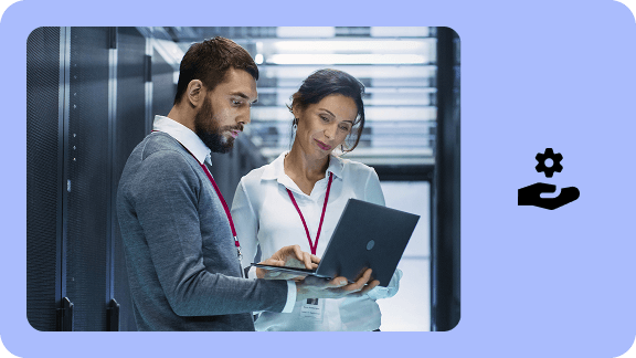 IT specialists working with a laptop in front of a server cabinet