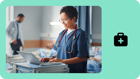 Healthcare professional working on a laptop in a hospital ward. The image represents digital healthcare and cloud solutions for the healthcare sector.